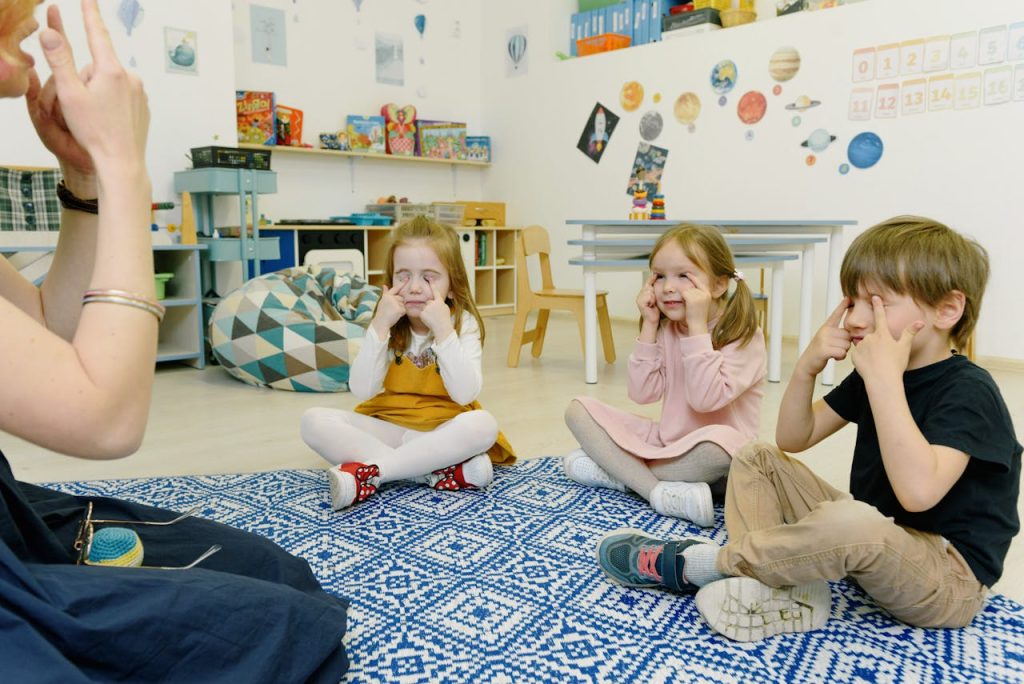 Group of children in a kindergarten class with tutor, playing and learning in a colorful room.